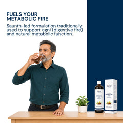 A man in a dark teal shirt drinks from a glass having digesto care juice by Triphal on a wooden table, with a bottle and its box displayed next to a small potted plant. The scene is split into a white left side with promotional text and a dark navy blue right side.